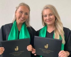 Runners-up Linnéa Asklöf and Elin Antus Flyckt, stand together in their graduation robes, holding diplomas.