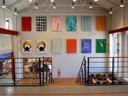 En stor vägg med färgglada abstrakta tavlor i rader. 