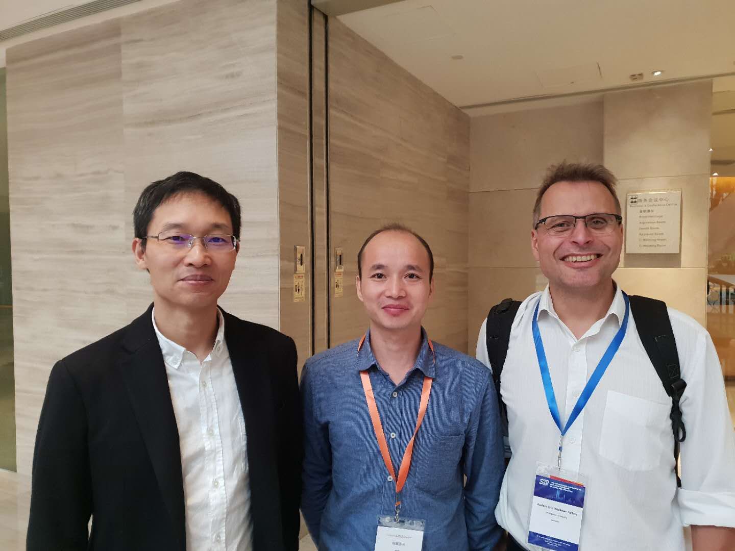 Haiping Cao, Zeng och Anders Jarfors står tillsammans i korridoren på ett konferenscenter.
