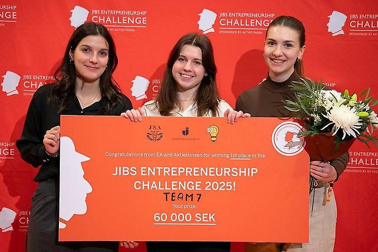 Tre personer står med en prischeck